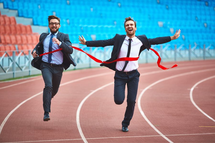 Two Men Running Towards A Finish Line Of A Race