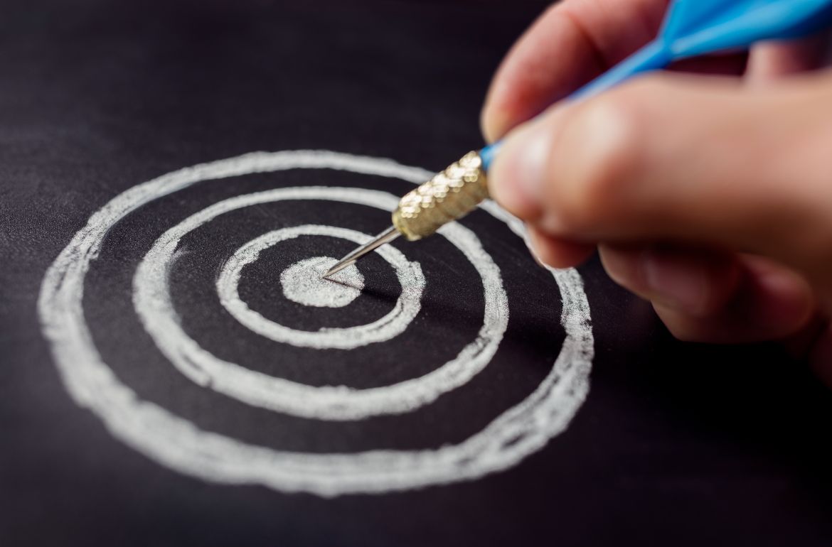 A hand of a productivity coach holding a dart that has hit a bullseye