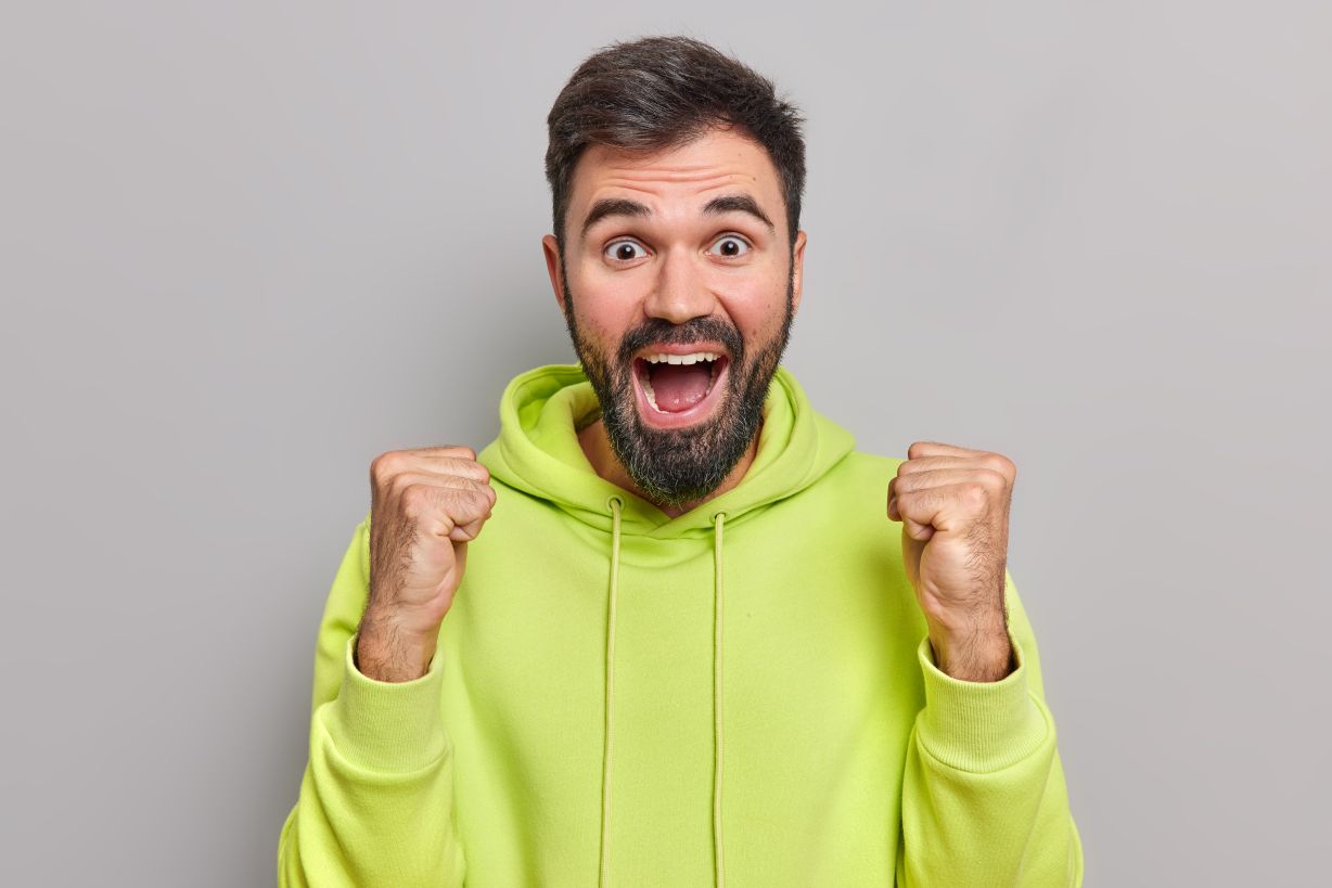 Cheerful bearded man raises fists in victory