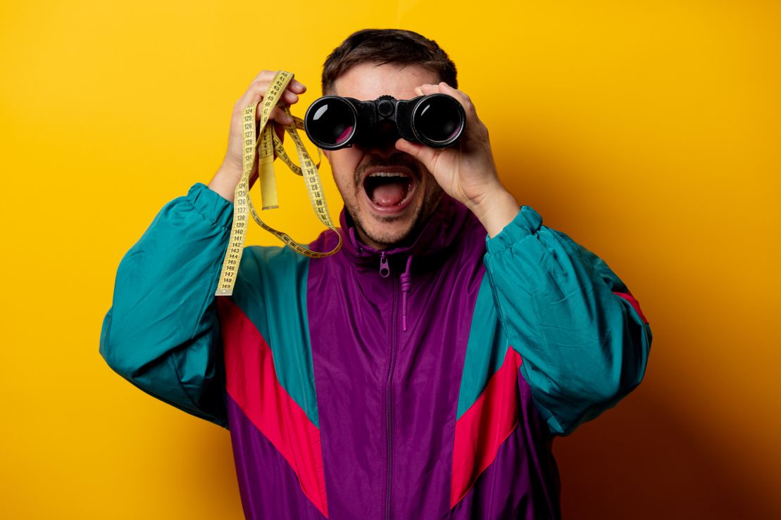 Man in 90s tracksuit with measuring tape and binoculars looking for trends and opportunities for marketing