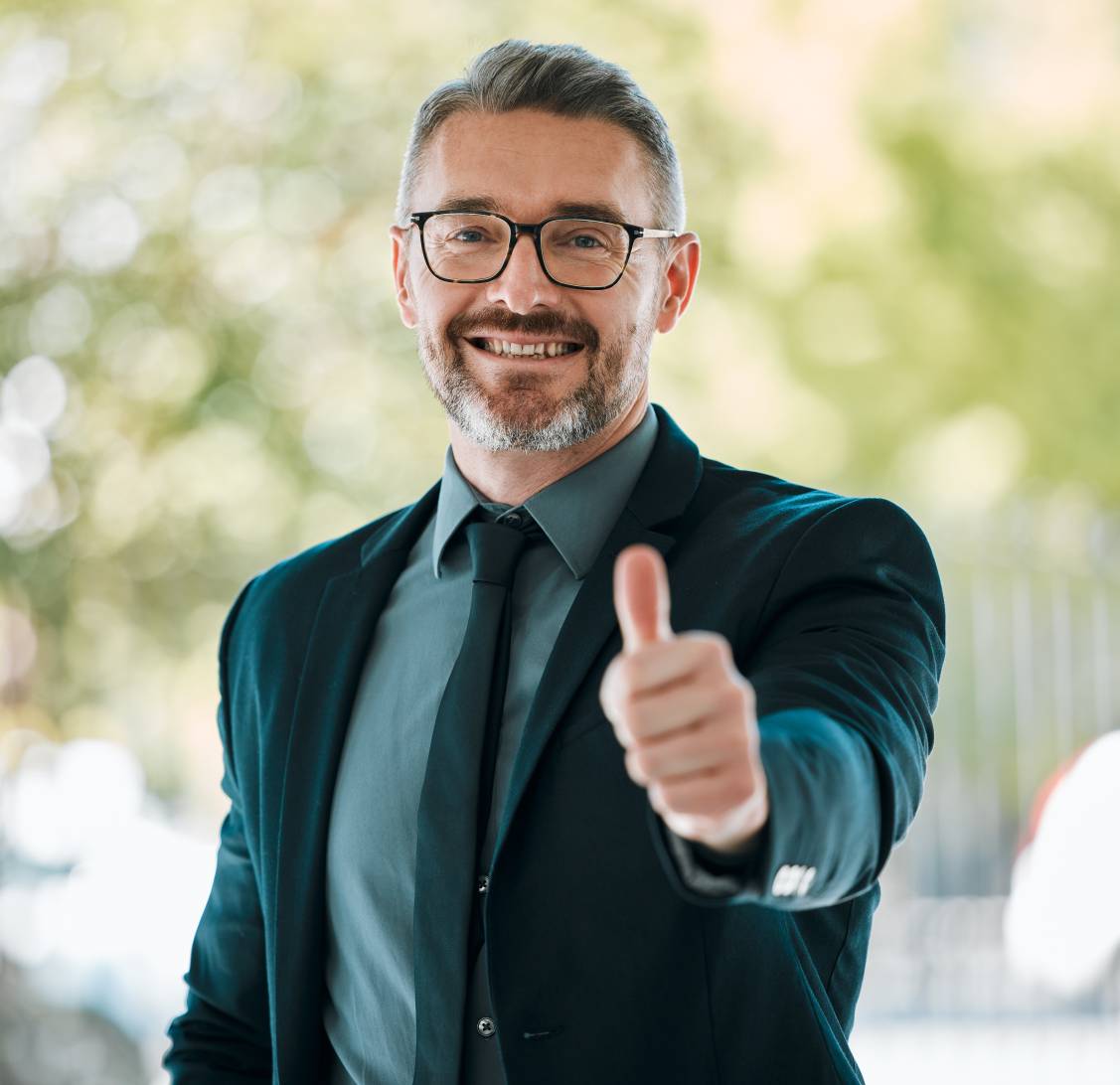 Business man holding a thumbs up over a green background