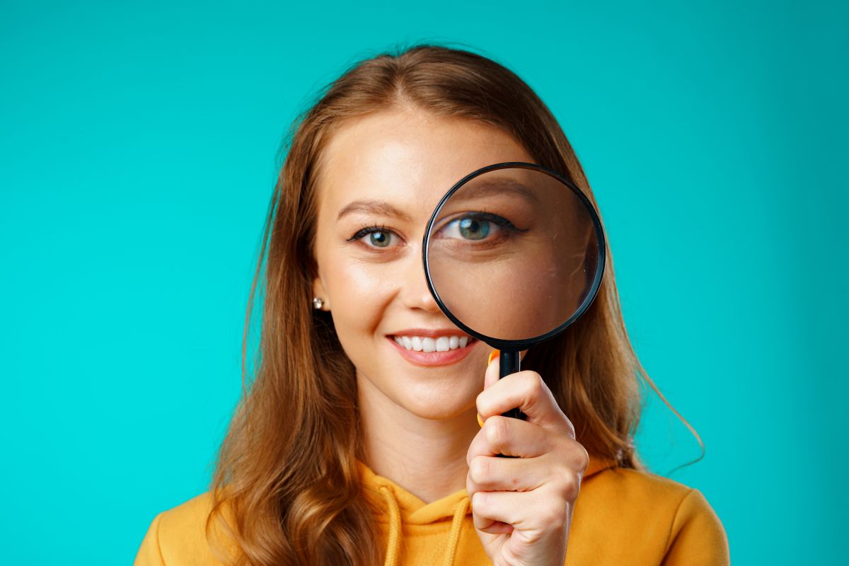 Young smiling woman looking through magnifying glass to find the right eCommerce specialist