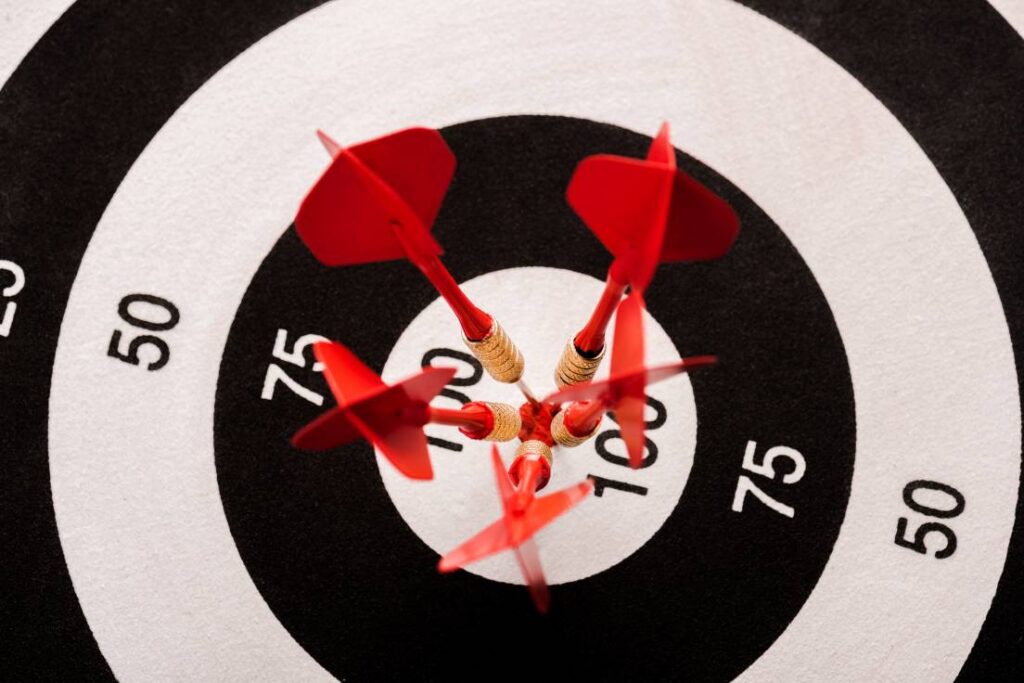 Top view of black and white dartboard with 5 red darts symbolizing the 5 Ps of marketing