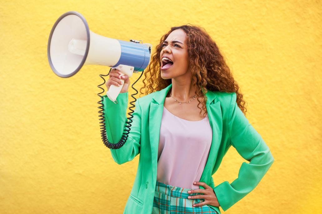 Woman holding a megaphone depicting how strong a call-to-action a creative copywriter should use