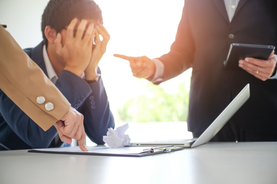 Colleagues bullying an employee, leading to visible emotional distress