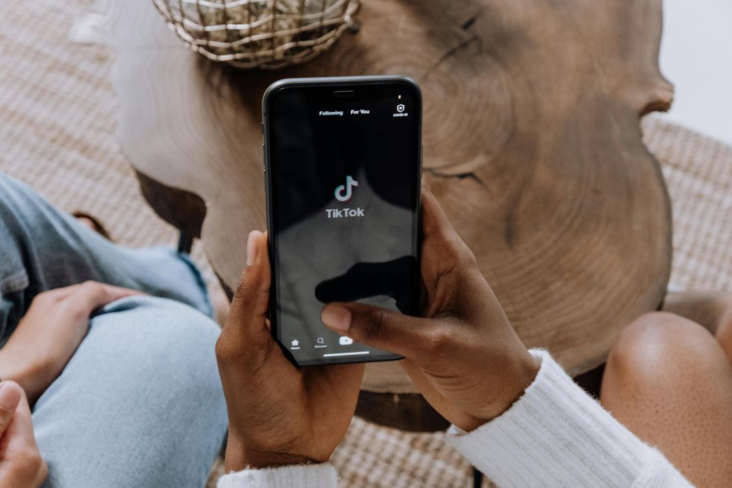 Man holding a phone with TikTok logo on screen