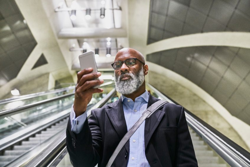 Mature Businessman Using Smartphone Escalator Reading Emails