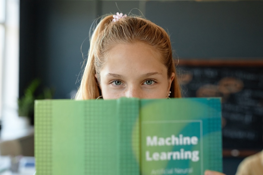 Schoolgirl Reading a Book About Machine Learning ML