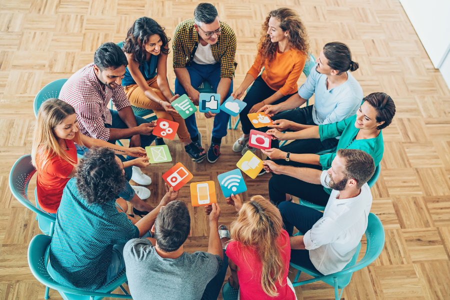 A group sitting in a circle, holding social-media icons, engaged in a discussion