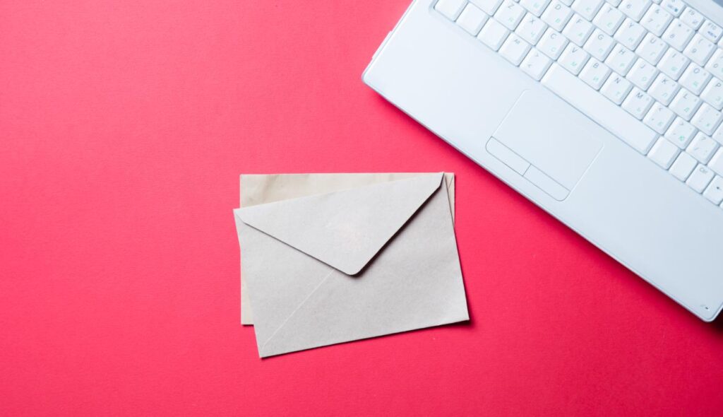 Envelopes and laptop on red background