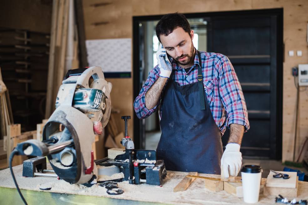 Portrait of carpenter calling by smart phone at the workshop