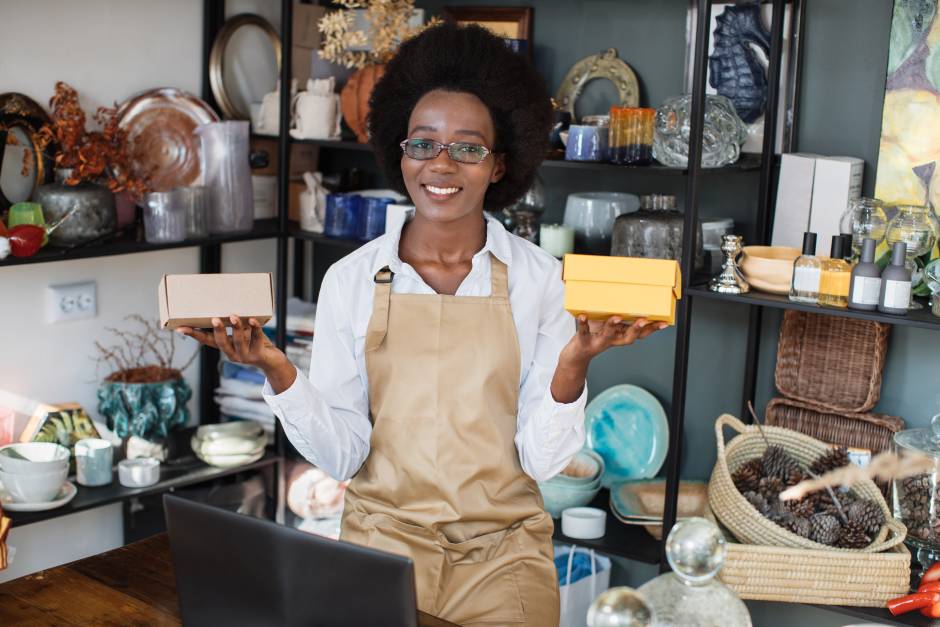 Smiling saleswoman sitting at decor shop with laptop